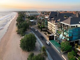 A coastal hotel with a beachfront view, multiple floors, and a restaurant on the ground level.