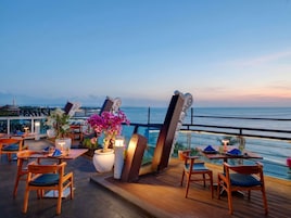 A rooftop terrace with tables and chairs, overlooking a body of water.