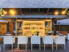An outdoor bar area with wicker chairs and a variety of bottles.