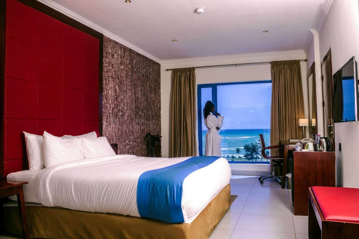 Relax in this spacious room with a large bed, desk, and TV, offering a stunning ocean and city view.