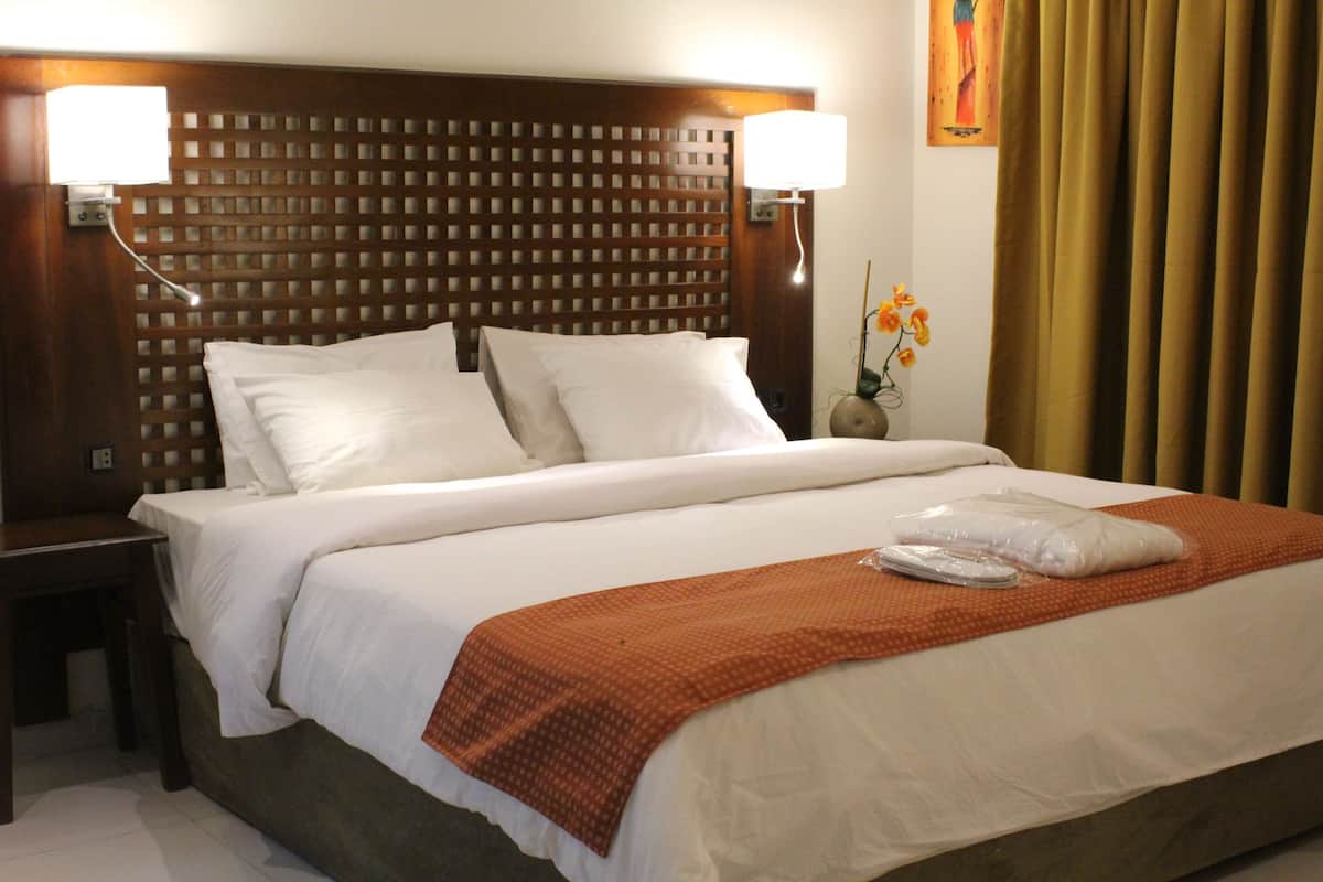 Relax in a cozy retreat with a neatly made bed, two nightstands, and a vase with fresh flowers.