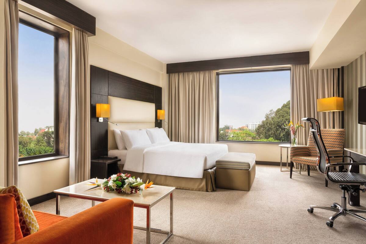 Ein Hotelzimmer mit einem großen Bett, einem Schreibtisch, einem Stuhl und einem Fernseher.