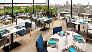 Un restaurant situé sur le toit d’un immeuble, avec une terrasse, de grandes fenêtres et une vue sur la ville.