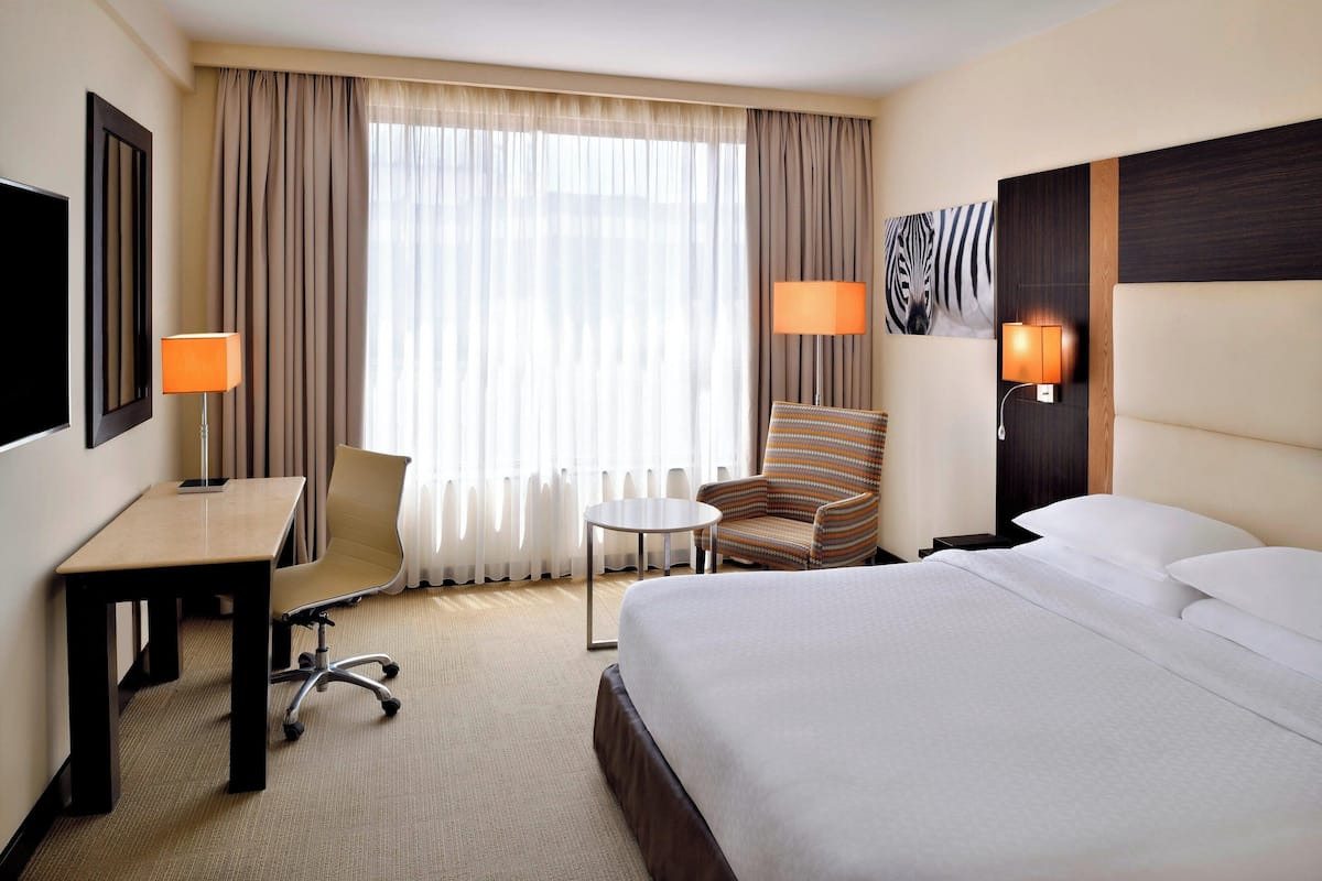 Ein Hotelzimmer mit Bett, Schreibtisch, Stuhl, einem kleinen Tisch und zwei Lampen.
