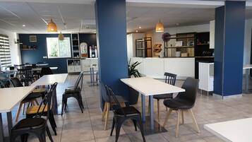 A modern dining area with tables and chairs, a kitchen area, and a counter with a menu.