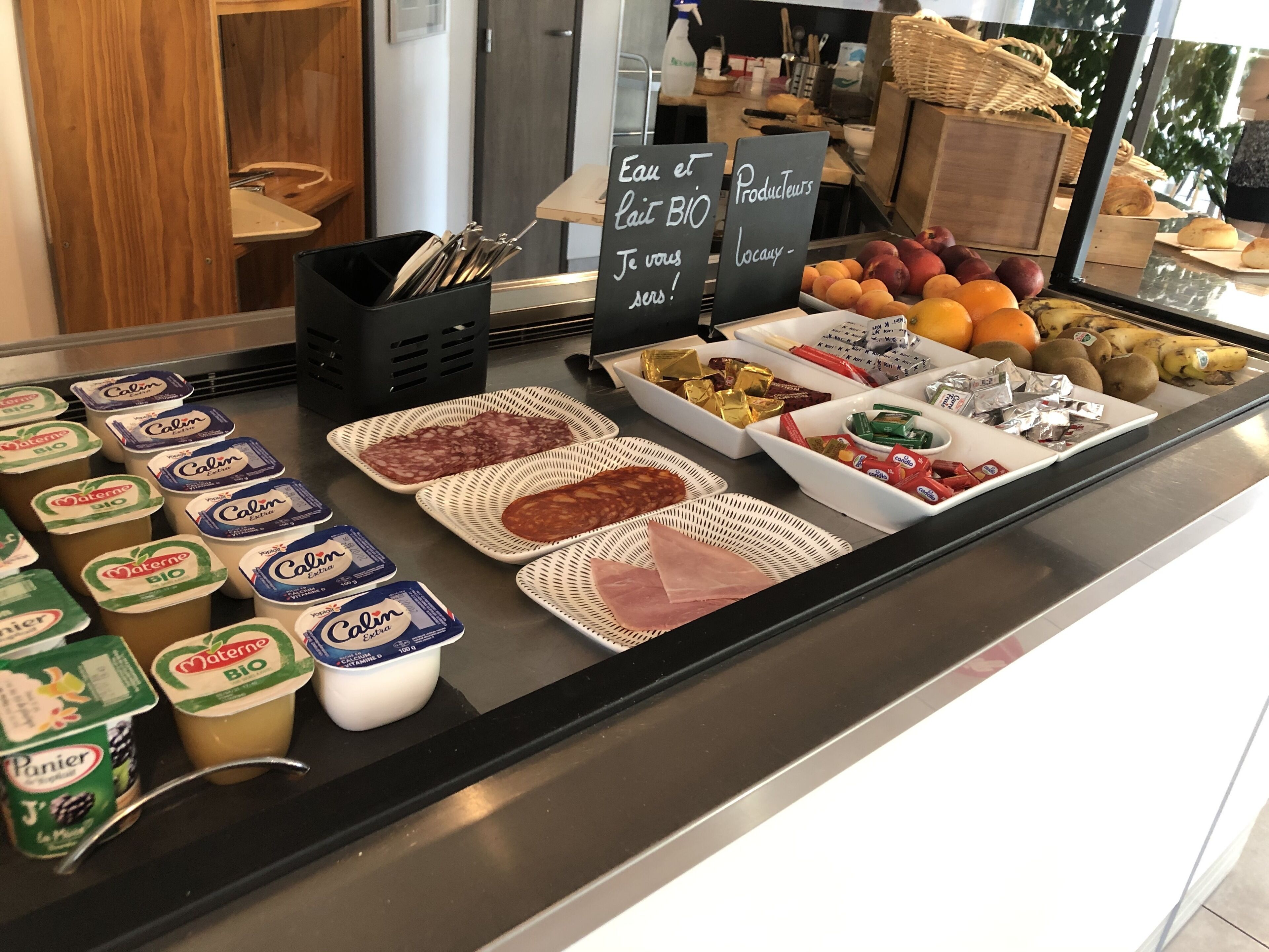 A breakfast buffet with various food items including dairy products, meats, and fruits.