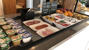 Un buffet de petit-déjeuner proposant une variété d’aliments, notamment des produits laitiers, des viandes et des fruits.