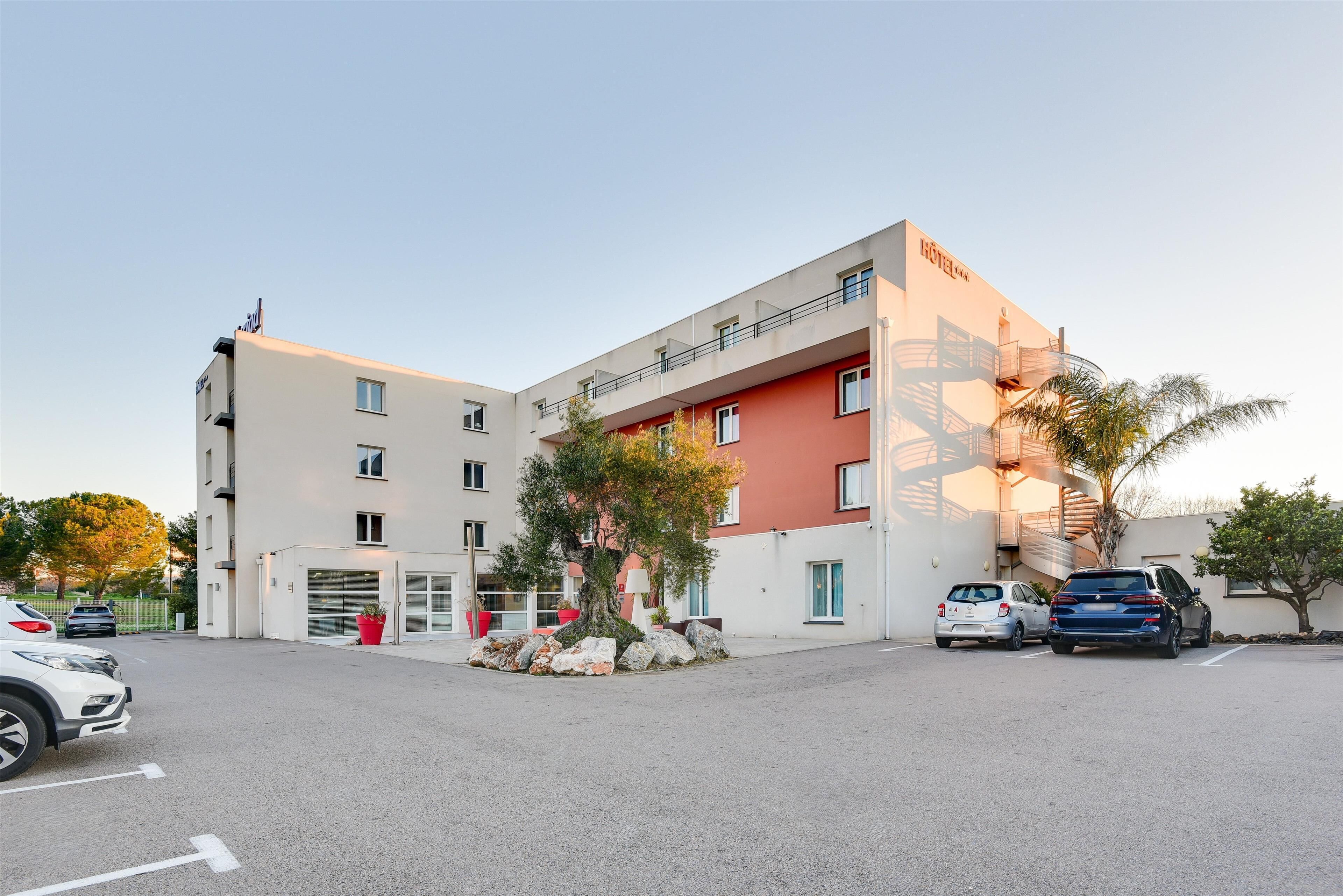 Un hôtel au design moderne, doté d’un parking et où quelques voitures sont garées.