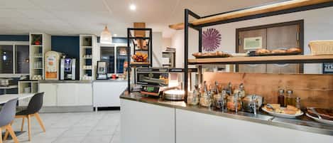 Een moderne keuken met een koffieapparaat, een magnetron en diverse etenswaren.