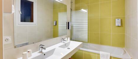 A bathroom with two sinks, a mirror, a window, and a bathtub.