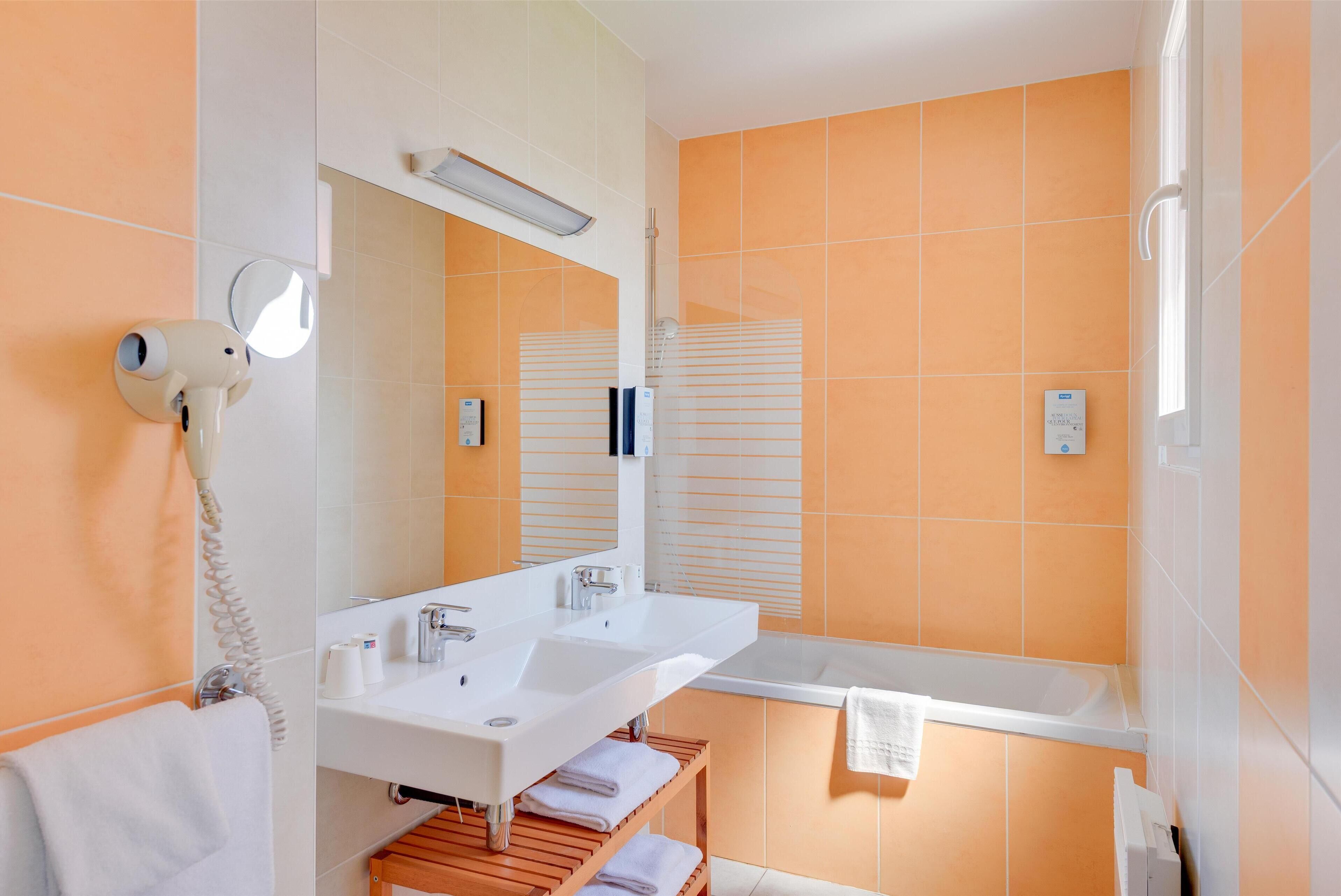 A modern bathroom with two sinks, a mirror, a hairdryer, and a shower.