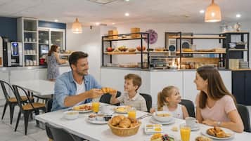 A family dining in a modern cafe with a white table, breakfast items, and a variety of food and drink options.