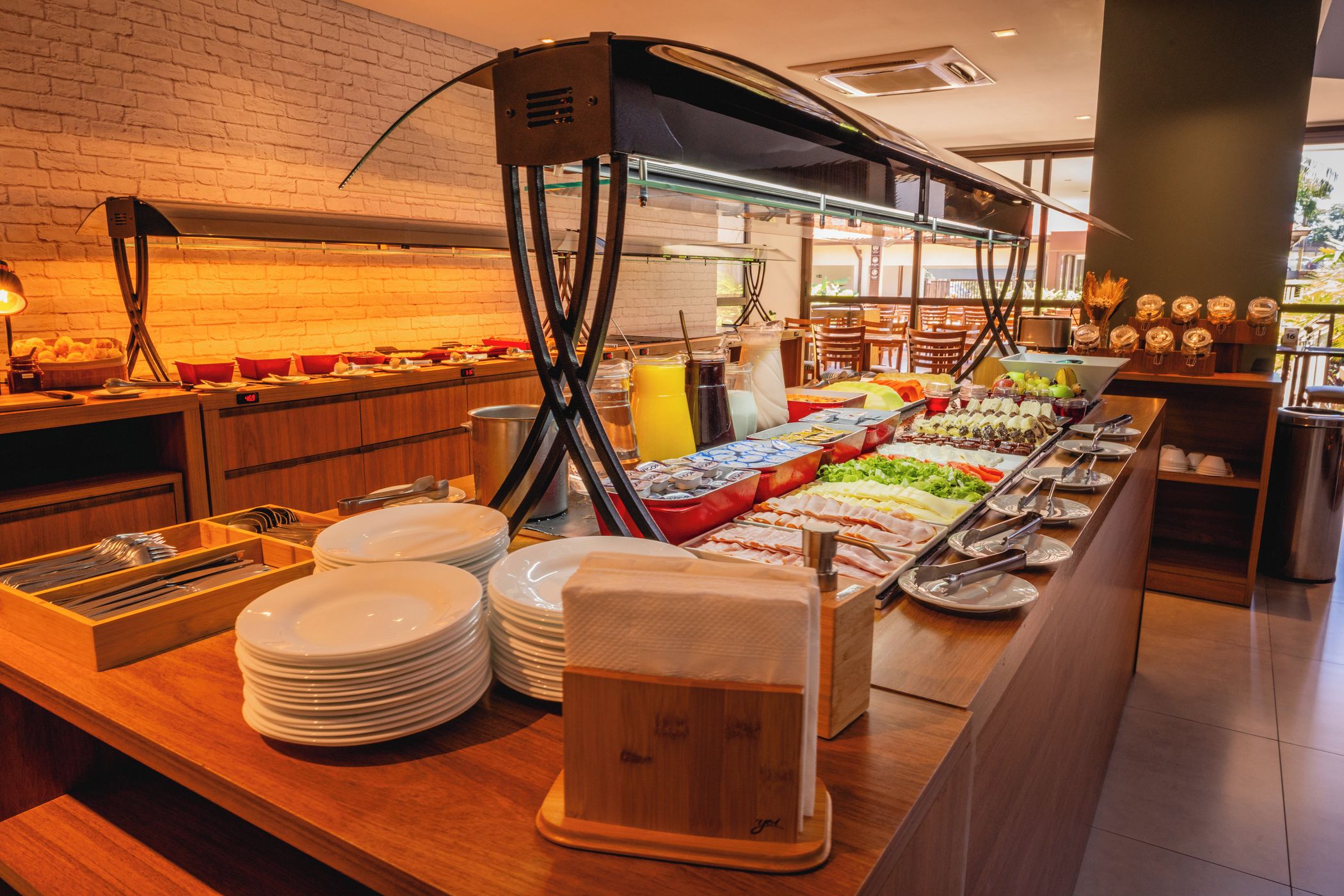 A buffet setup with various food items and condiments, including fruits, vegetables, and beverages.