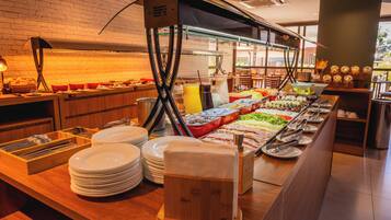 A buffet setup with various food items and condiments, including fruits, vegetables, and beverages.