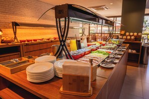 A buffet setup with various food items and condiments, including fruits, vegetables, and beverages. - Fildi Hotel & Eventos (Sumare)