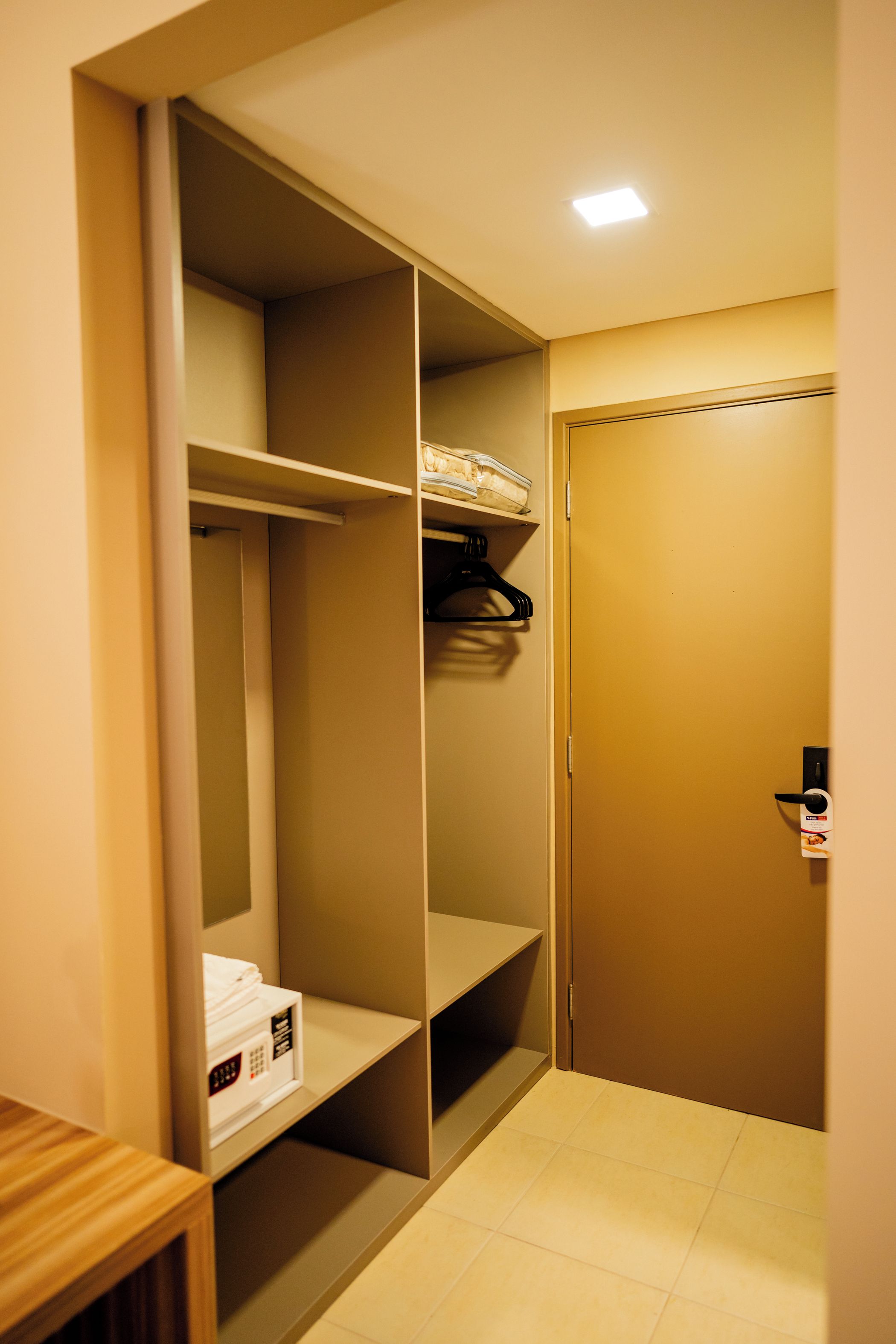 A walk-in closet with shelves, a hanging rod, and a door with a lock.