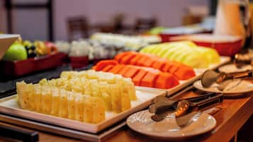 Mesa de buffet com diversos alimentos, incluindo frutas e legumes fatiados.
