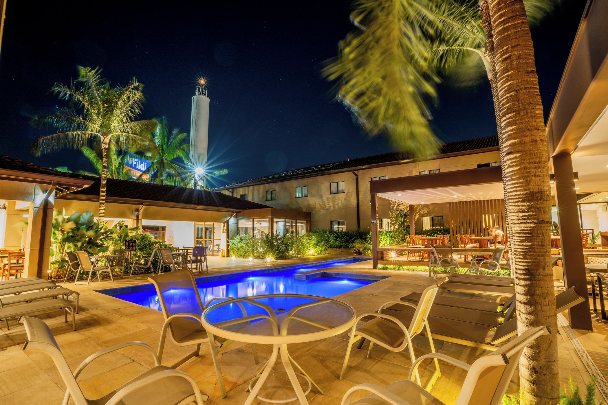 A poolside area with lounge chairs and a swimming pool at night.