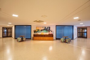 A spacious lobby with a reception desk, two seating areas, and a large abstract painting on the wall. - Fildi Hotel & Eventos (Sumare)