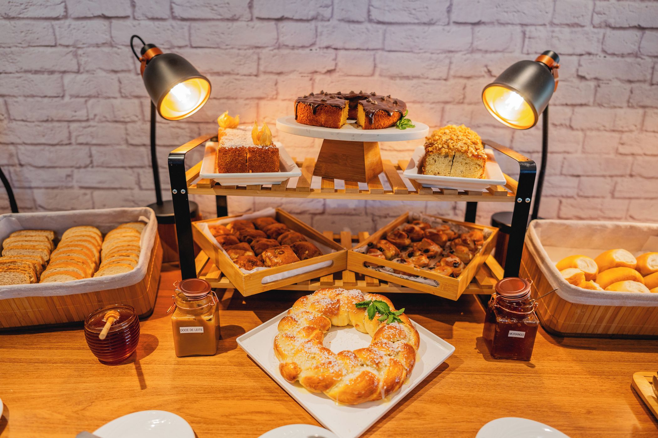 A buffet table with various baked goods, including bread, pastries, and a honey jar.