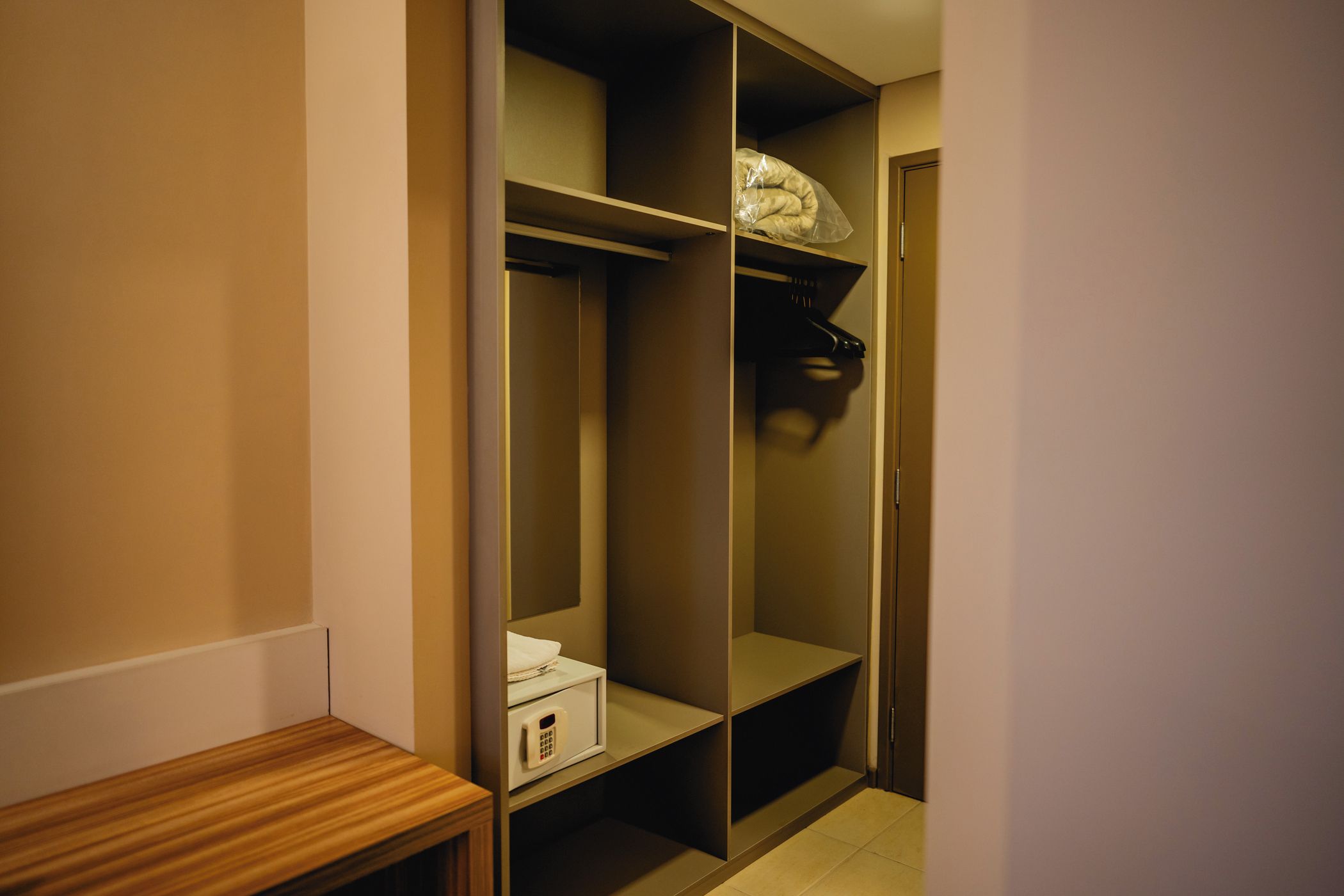 Um closet espaçoso com prateleiras, cabideiro e uma pequena mesa.
