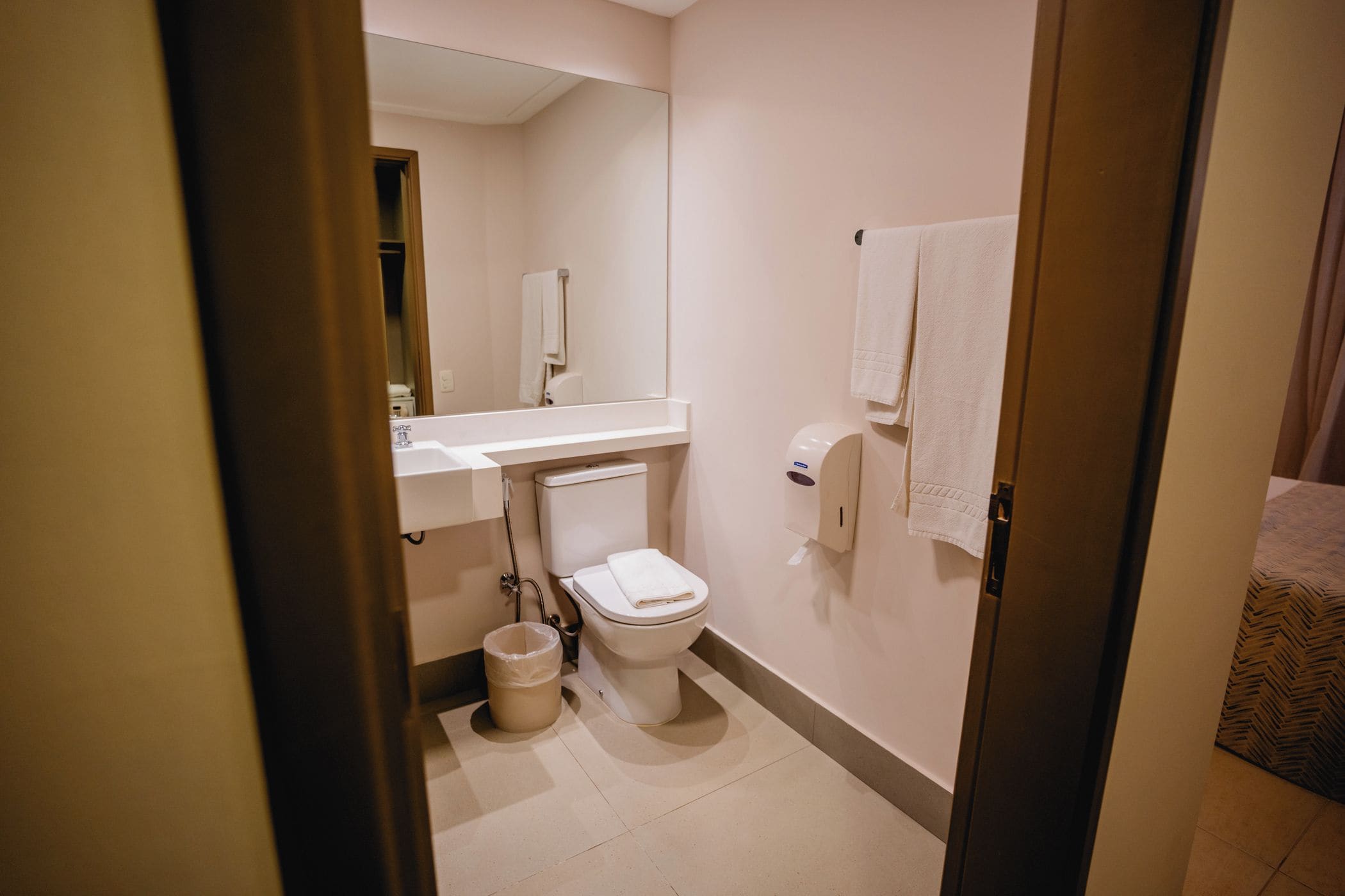 A compact bathroom with a toilet, sink, and a towel rack.