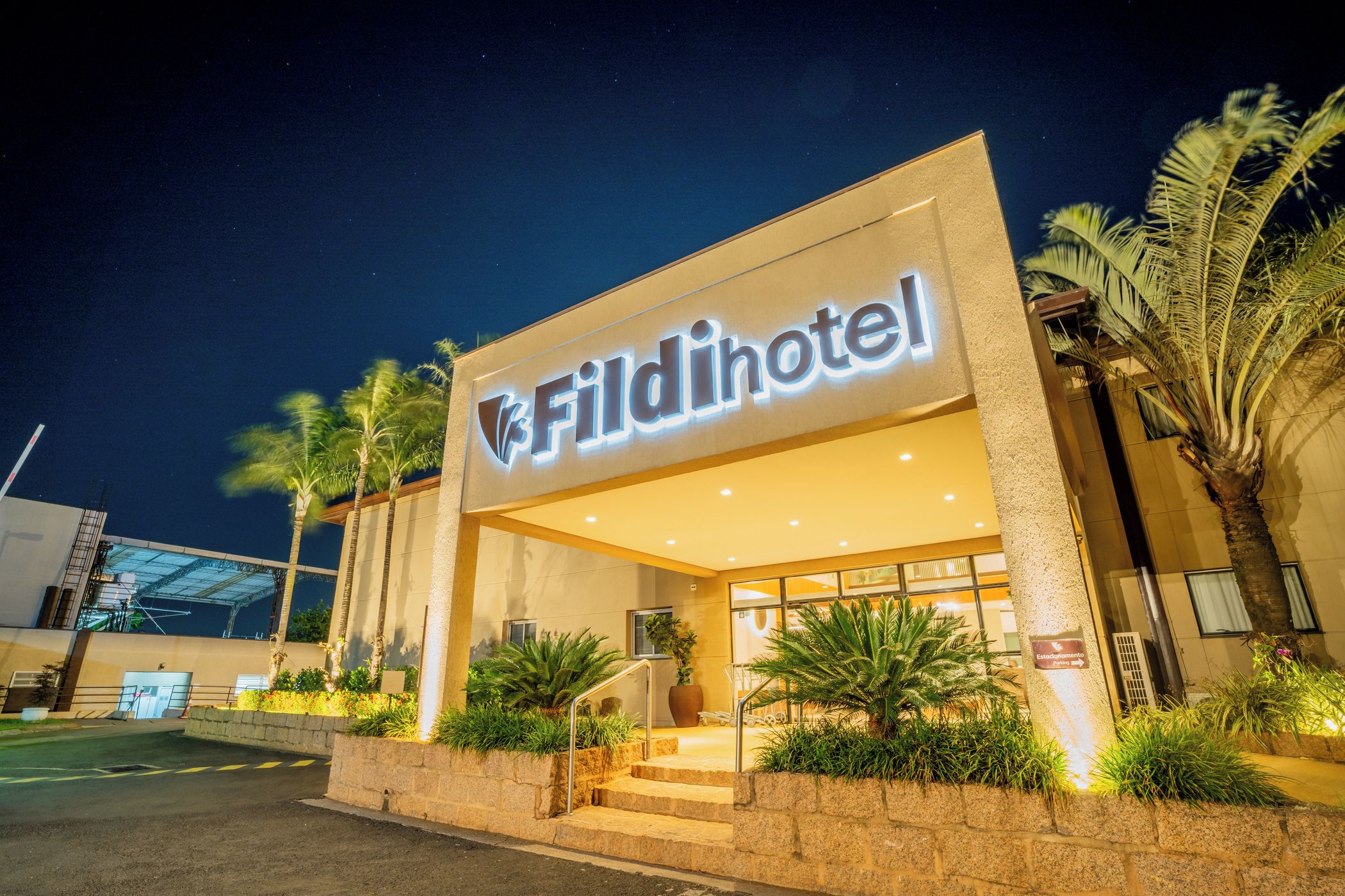 Entrada de um hotel com uma placa indicando 'Fildihotel' e uma escadaria que leva à entrada.