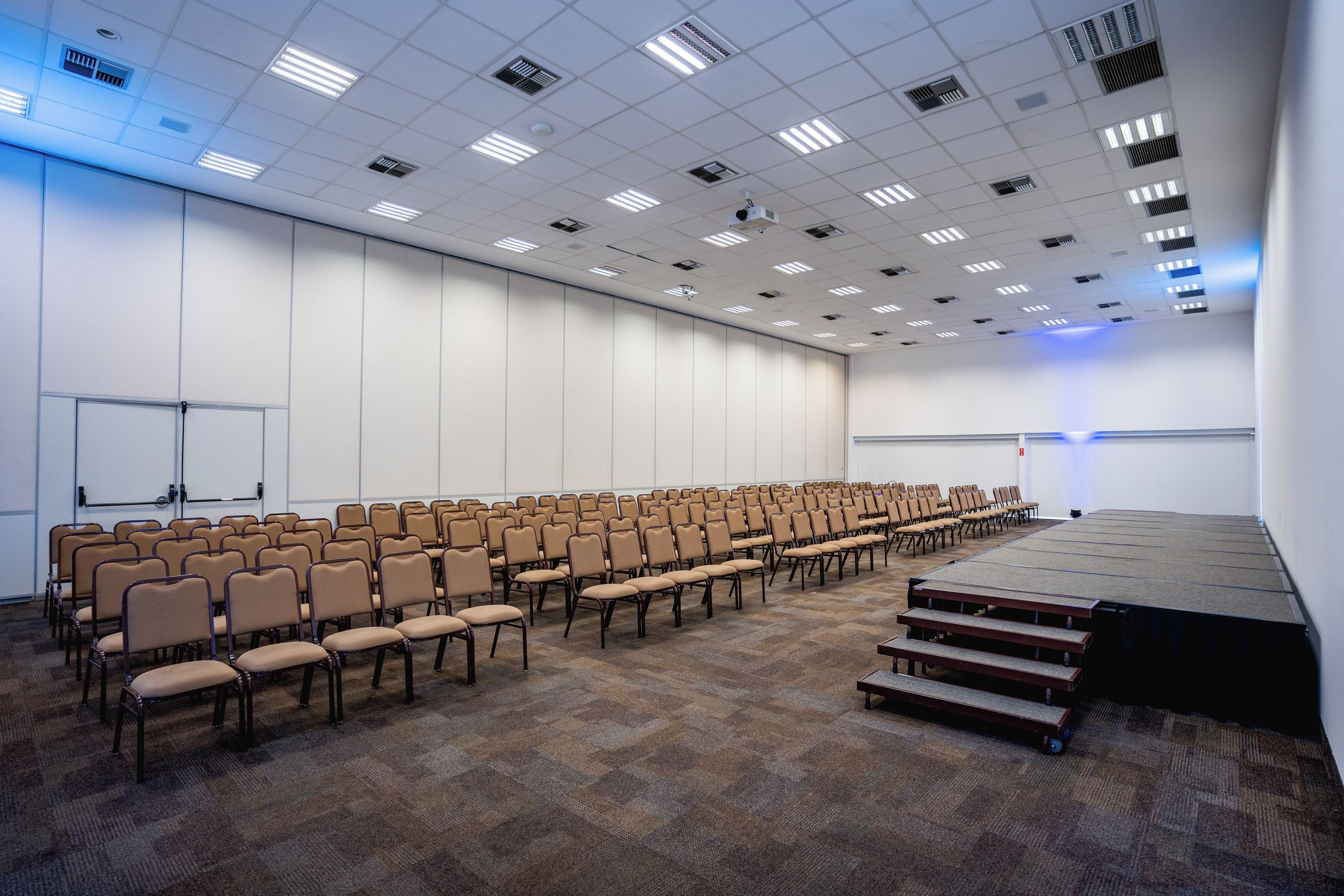 A conference room with rows of chairs, a stage, and a whiteboard.