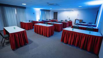 A conference room with multiple tables, chairs, and a projector screen.