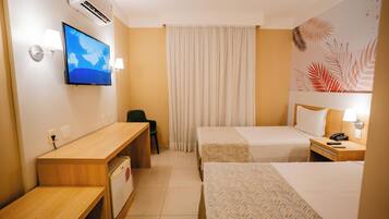 Ein Hotelzimmer mit Schreibtisch, zwei Betten, Fernseher, Telefon und einer Wand-Klimaanlage.