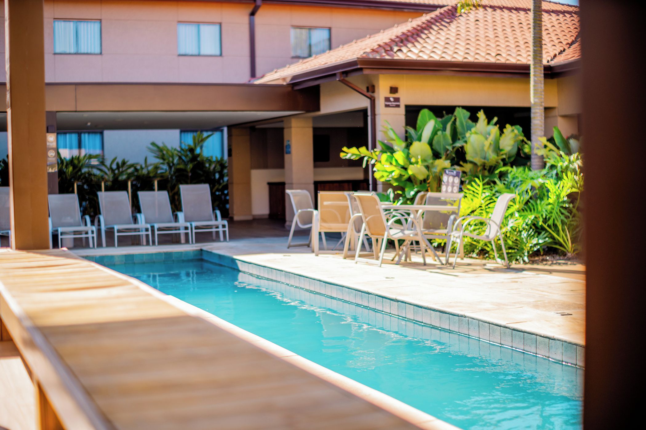 A swimming pool with lounge chairs and a covered patio area.