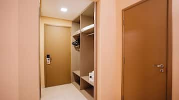 A hallway with a door leading to a closet containing shelves and a microwave.