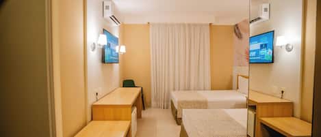 Una habitación de hotel con dos camas, un escritorio, una silla y un televisor.