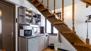 A compact kitchen with a built-in microwave, a small refrigerator, and a wooden staircase leading to an upper level. - Condominium Hakuba Goryu (Hakuba)