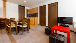 A dining area with wooden chairs and a table, a red bench, a television, and wooden doors. - Condominium Hakuba Goryu (Hakuba)