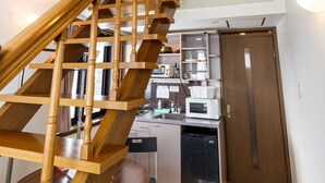 A wooden staircase leading to an upper floor with a skylight. A kitchen area is visible below, including a microwave and a refrigerator. - Condominium Hakuba Goryu (Hakuba)