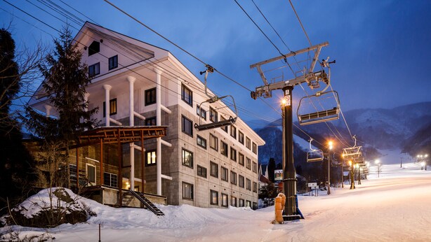 A modern hotel with a ski lift, snow-covered surroundings, and a mountain backdrop. - Condominium Hakuba Goryu (Hakuba)