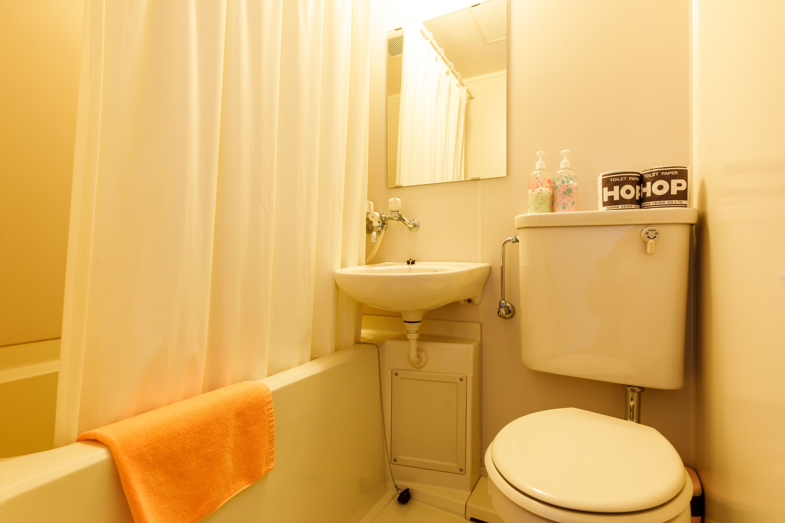 A bathroom with a white sink, toilet, and bathtub. There are two bottles of toiletries on the toilet tank.