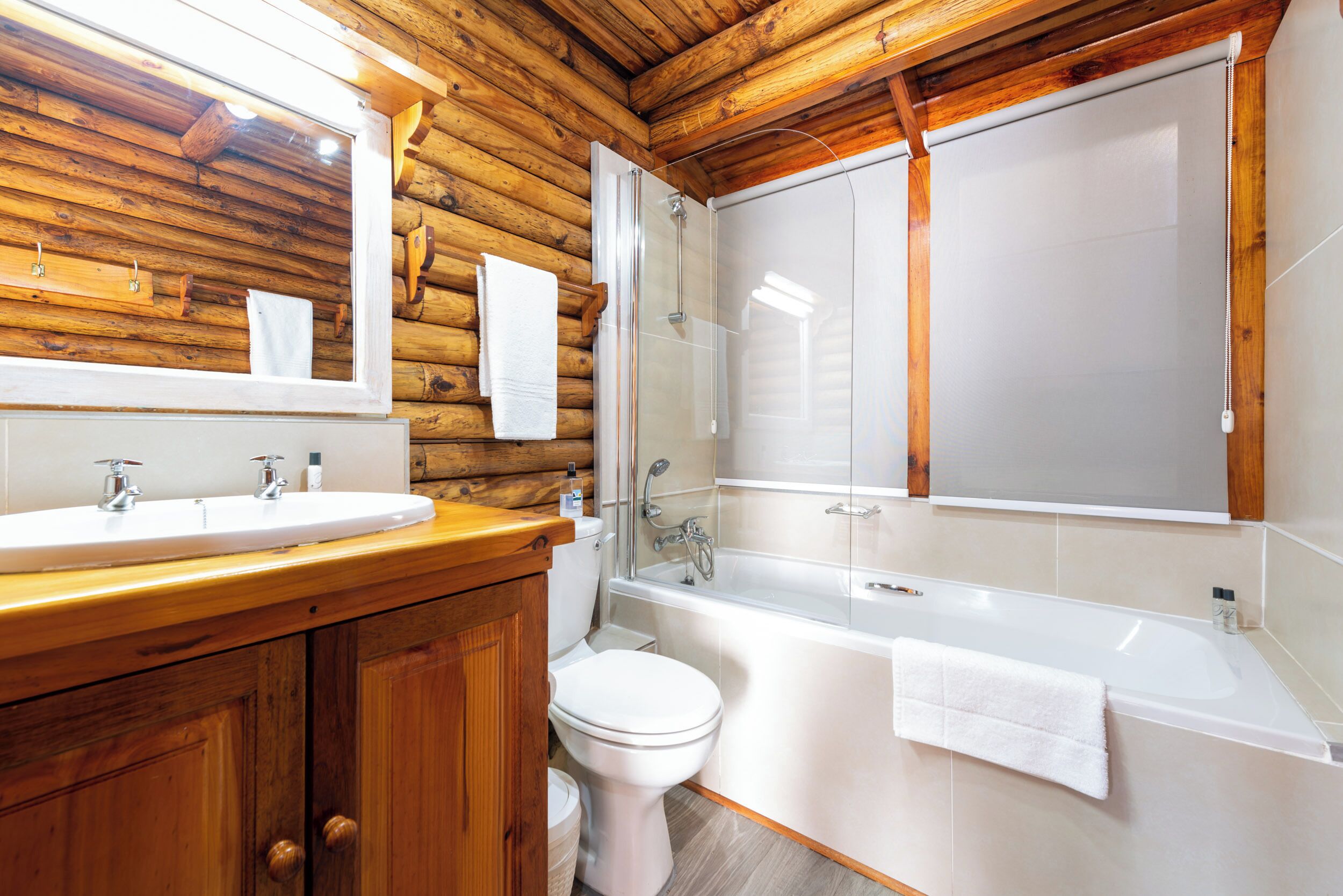 Baño de cabaña de madera con lavamanos, inodoro y bañera.