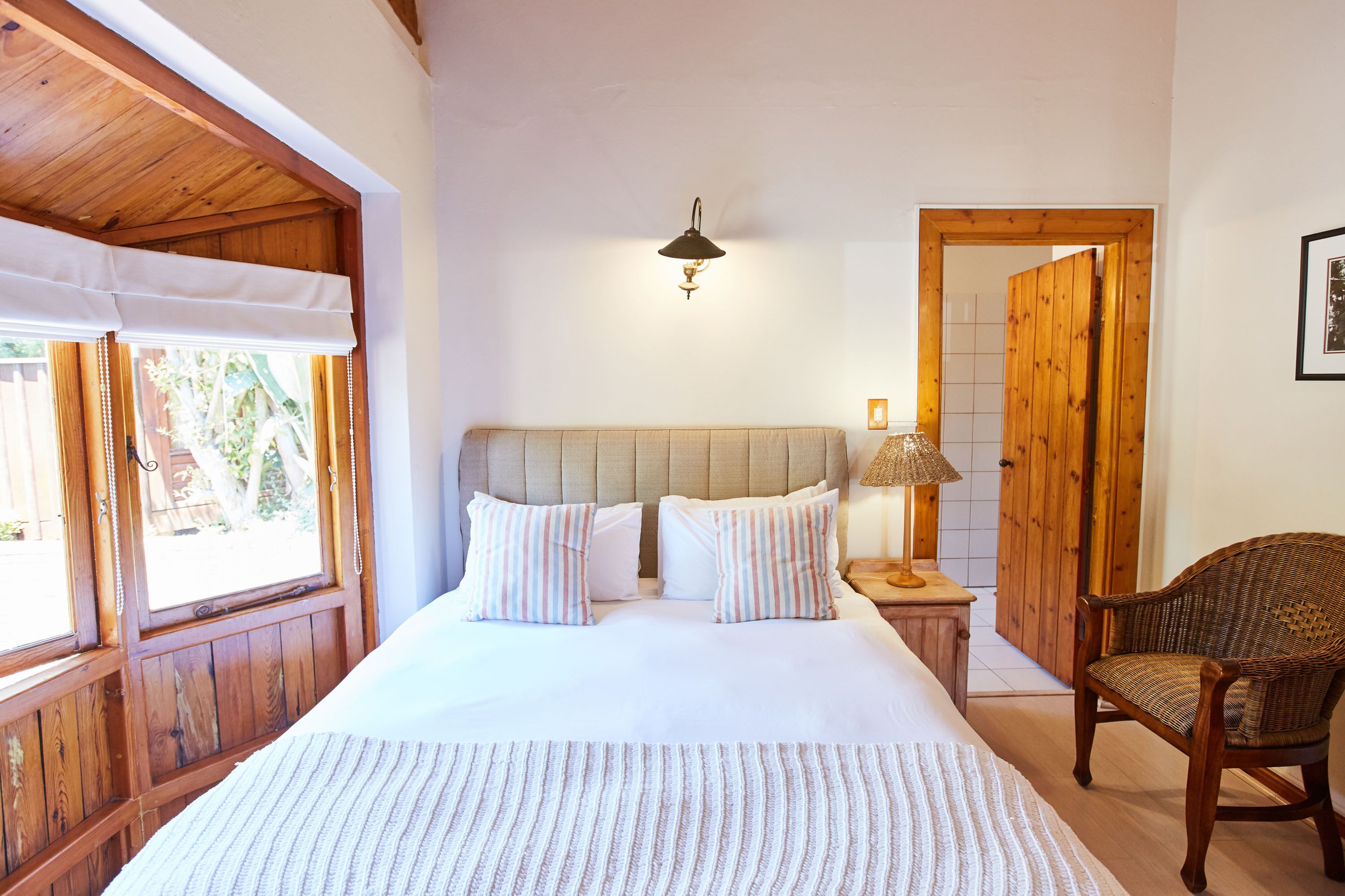 A bedroom with a large bed, wooden headboard, and a nightstand with a lamp.