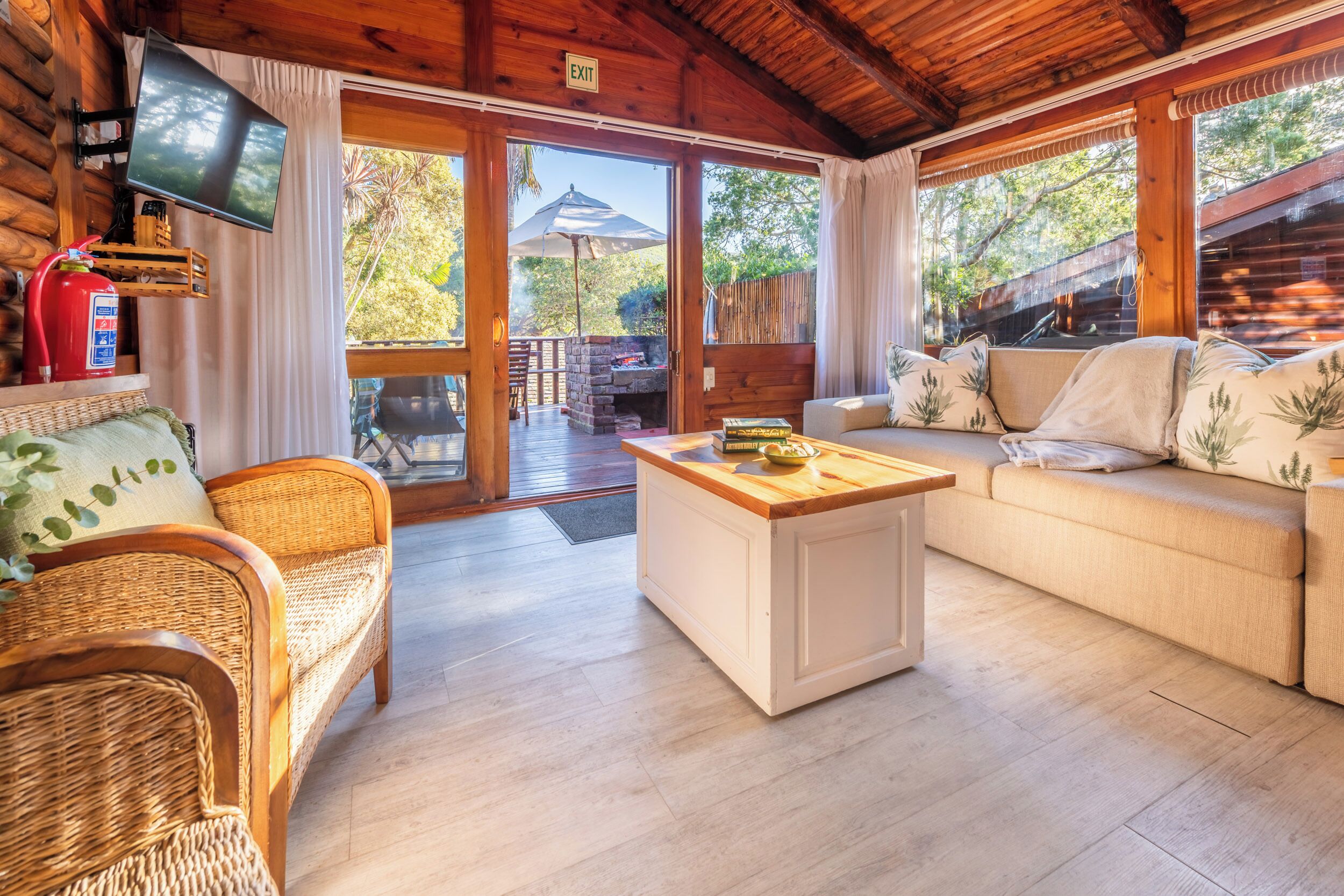 Een gezellig cabin interieur met een rieten bank, een witte bijzettafel en een comfortabele bank.