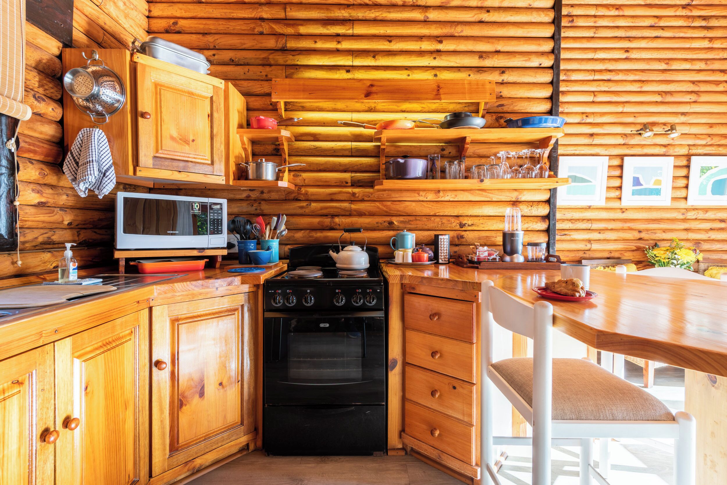 A wooden cabin kitchen with a stove, microwave, and wooden cabinets.
