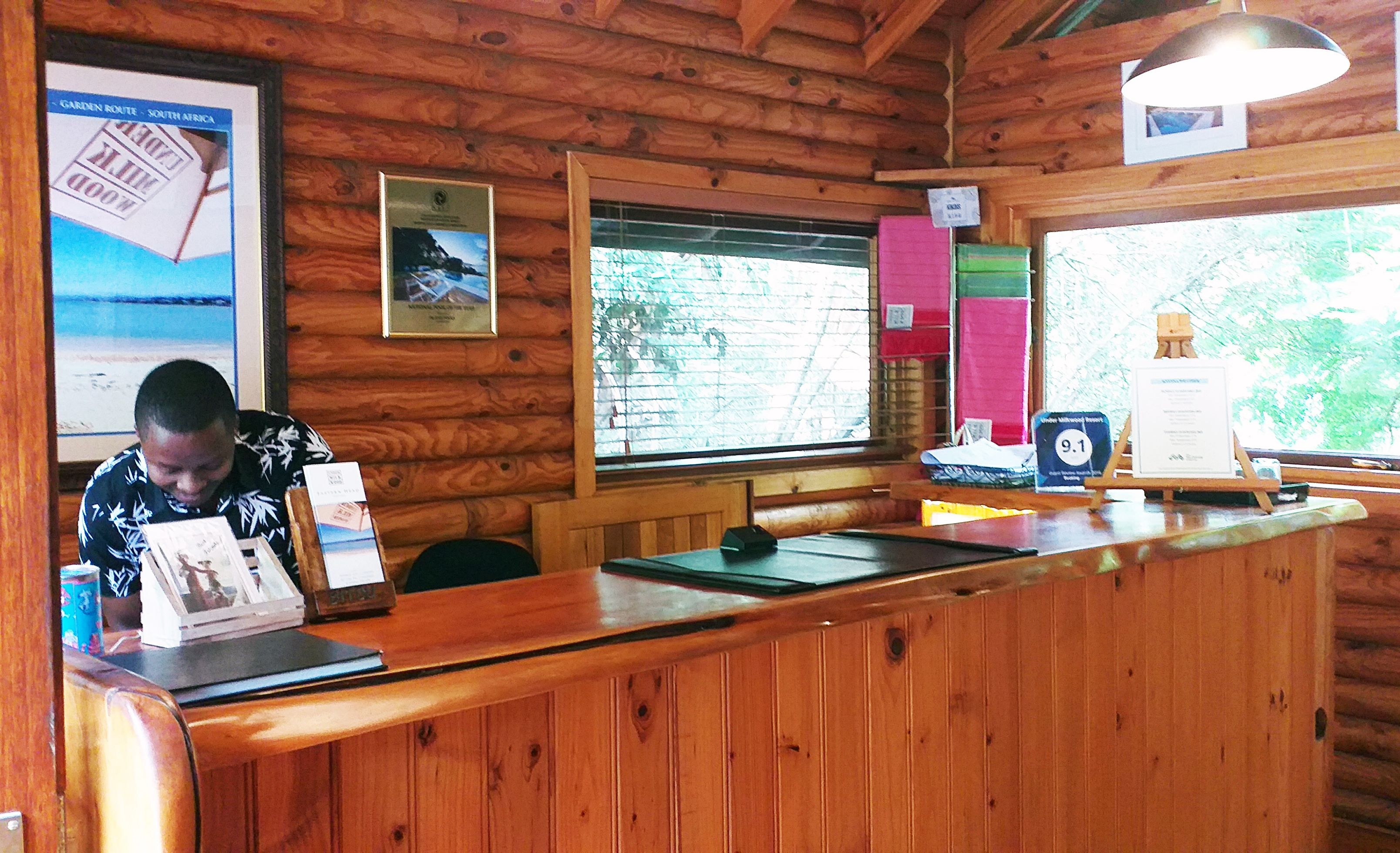 A wooden reception desk with a framed map and a framed photograph on the wall.