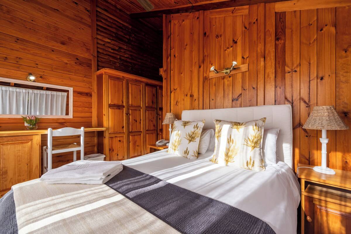 Ein Schlafzimmer mit Holzwänden, einem großen Bett, einem Schreibtisch und einem Sessel.
