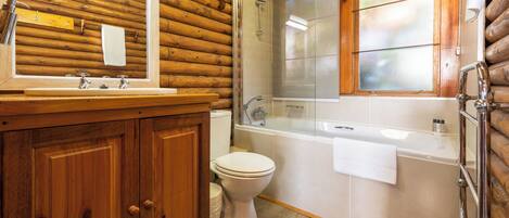 A wooden cabin bathroom with a wooden vanity, a toilet, a bathtub, and a shower.