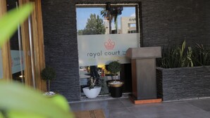 A hotel entrance with a sign reading "royal court" and a modern design featuring a stone facade and potted plants. - Royal Court Hotel (Ramallah)