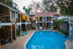 A swimming pool with a stone and brick house in the background. - The Tamarind Hotel Anjuna, Goa (Anjuna)