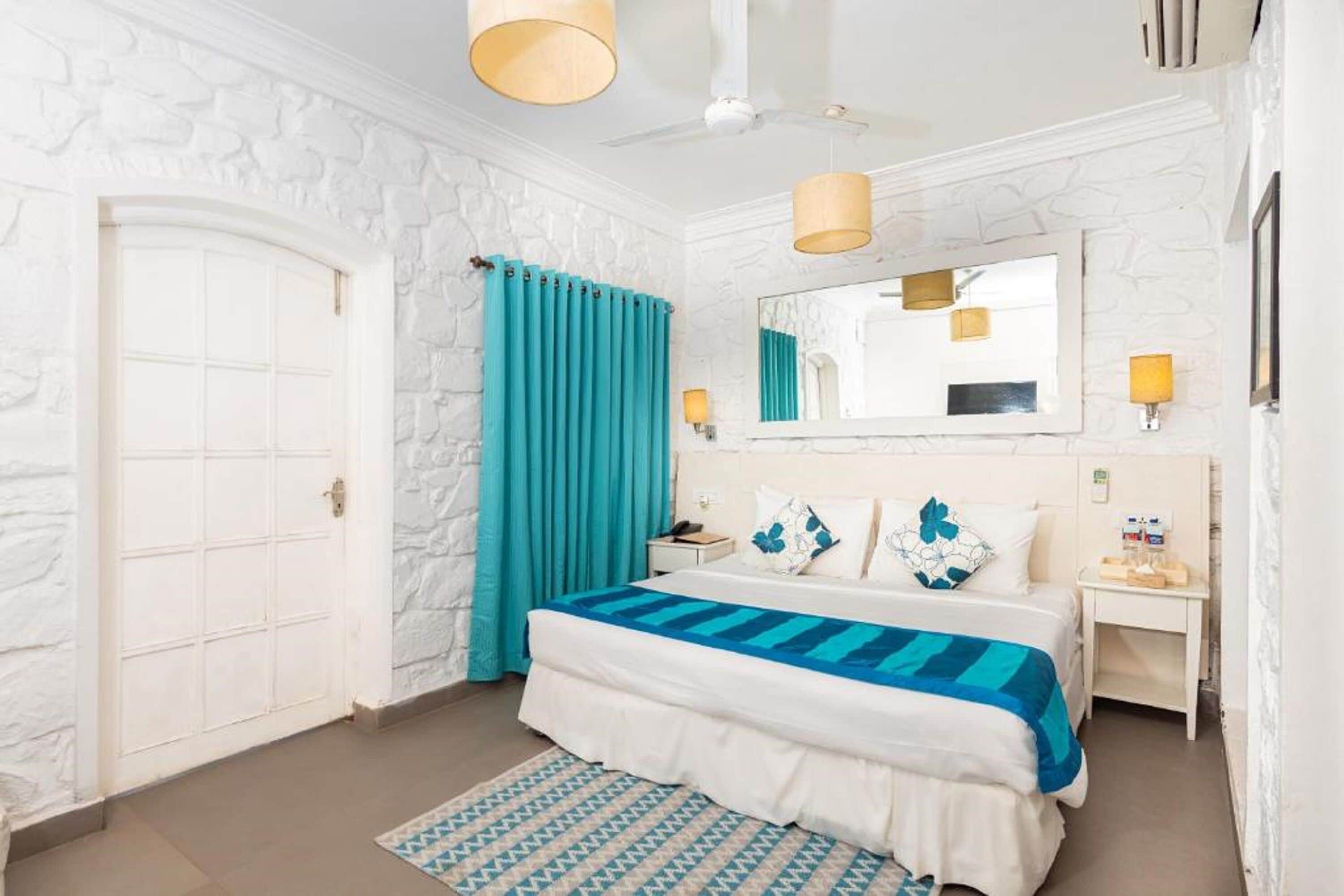 A bedroom with a bed, a nightstand, a mirror, and a door.
