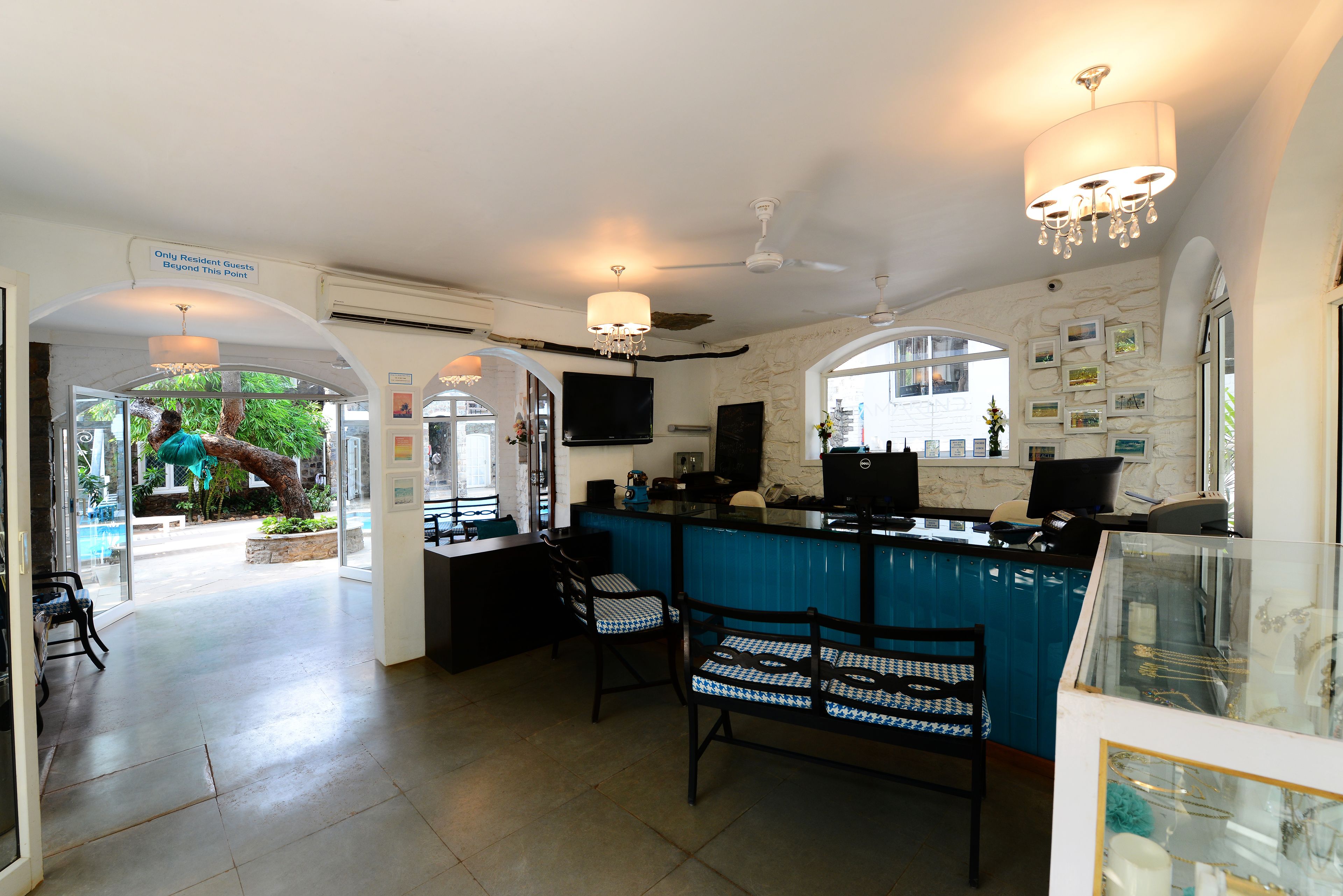 A hotel lobby with a reception desk, seating area, and a view of the outdoor pool area.