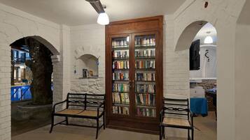 Une bibliothèque avec des étagères, une porte en bois et deux chaises.